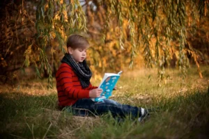 A boy reading a book - How to Foster a Love of Reading in Young Children - Queens Collegiate